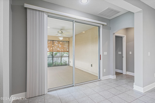 interior space featuring a textured ceiling, light tile patterned floors, and ceiling fan