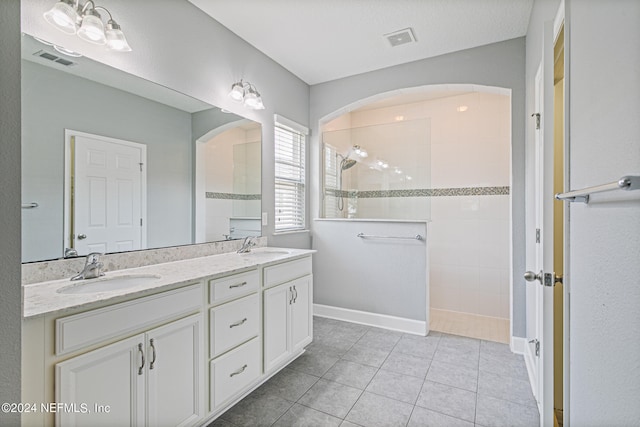 bathroom with a tile shower, tile patterned floors, and vanity