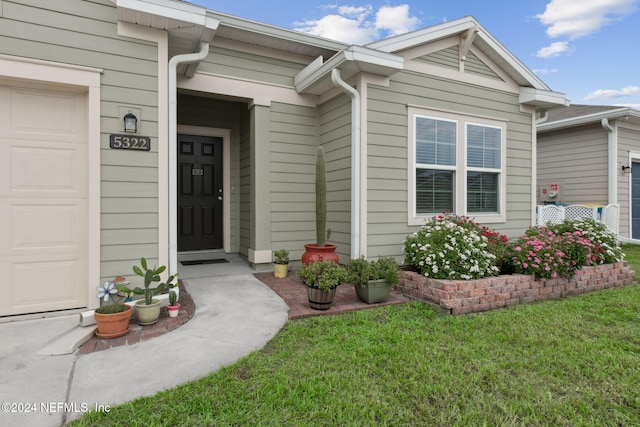 property entrance with a garage and a lawn