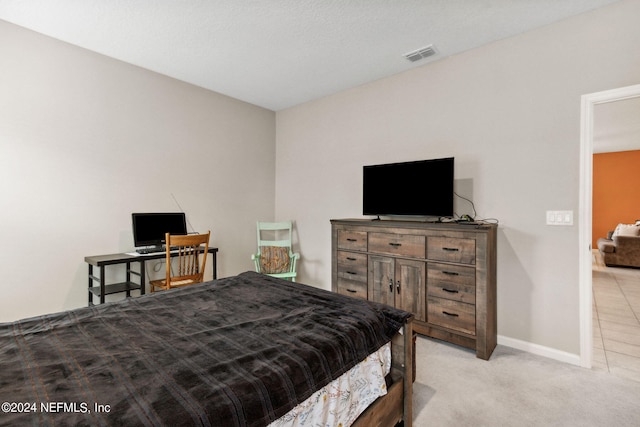 bedroom featuring light carpet and a textured ceiling