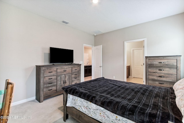 bedroom with light carpet and ensuite bath