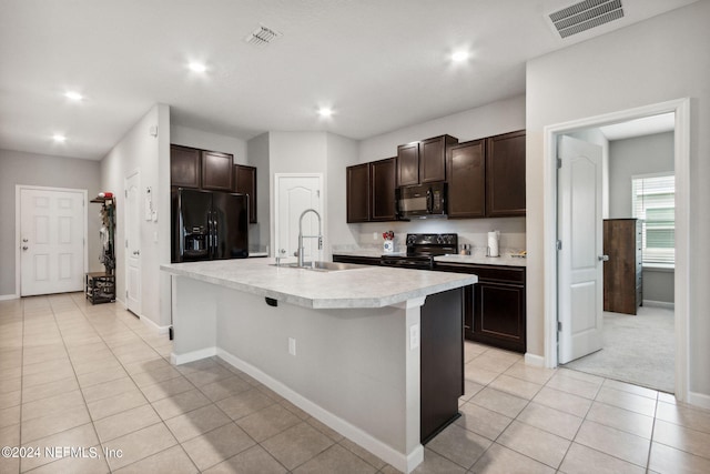 kitchen featuring sink, a kitchen island with sink, dark brown cabinets, and black appliances