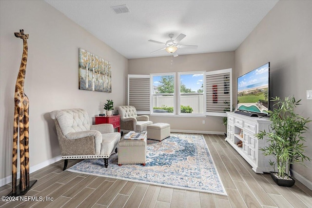 living area featuring ceiling fan, hardwood / wood-style flooring, and a textured ceiling