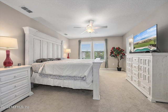 bedroom featuring light carpet, ceiling fan, and a textured ceiling