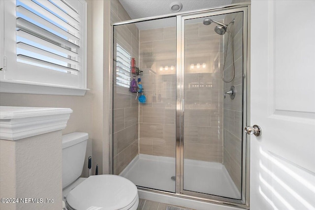 bathroom with a shower with door and toilet