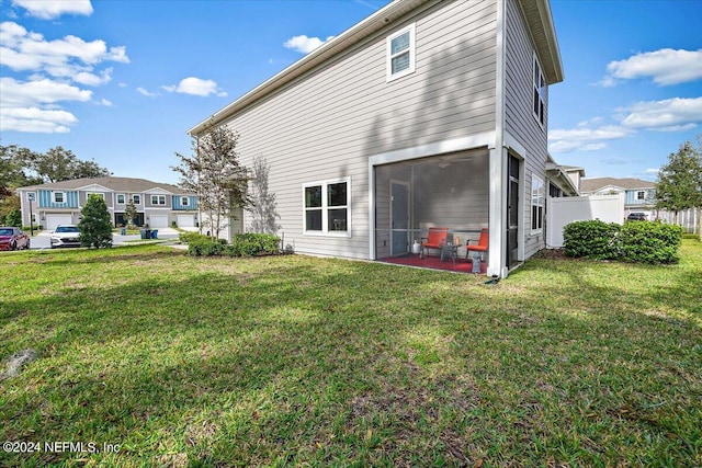 rear view of house featuring a lawn, a sunroom, and a patio area