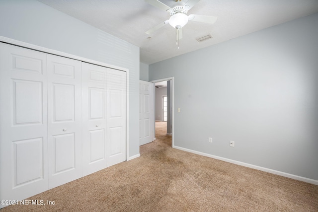 unfurnished bedroom with light carpet, ceiling fan, and a closet