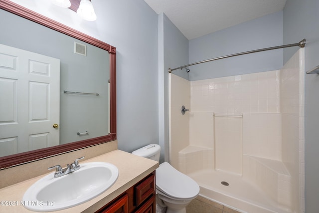 bathroom with tile patterned floors, walk in shower, vanity, and toilet