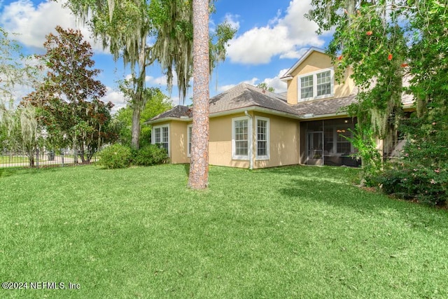 rear view of property featuring a sunroom and a yard