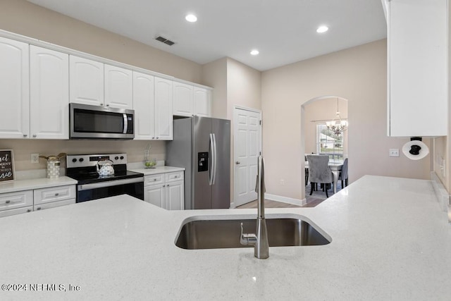 kitchen featuring stainless steel appliances, a notable chandelier, sink, and white cabinetry