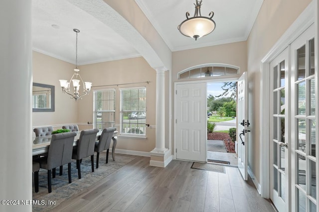 foyer with decorative columns, a healthy amount of sunlight, crown molding, and hardwood / wood-style floors