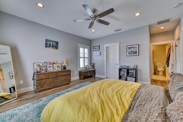 bedroom featuring a textured ceiling, ceiling fan, ensuite bathroom, and hardwood / wood-style flooring