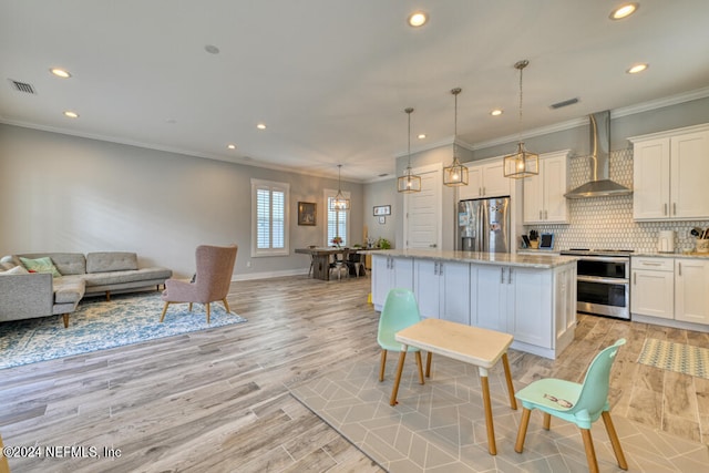 kitchen with light hardwood / wood-style floors, a center island, white cabinetry, wall chimney range hood, and appliances with stainless steel finishes