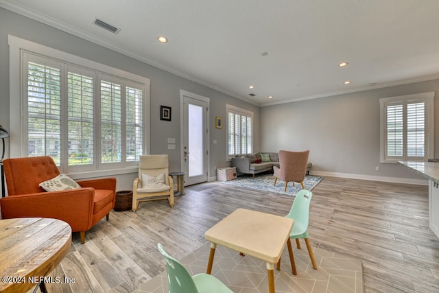 living room with light hardwood / wood-style floors, a healthy amount of sunlight, and crown molding