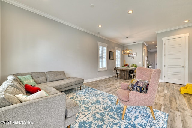 living room featuring light wood-type flooring, ornamental molding, and an inviting chandelier