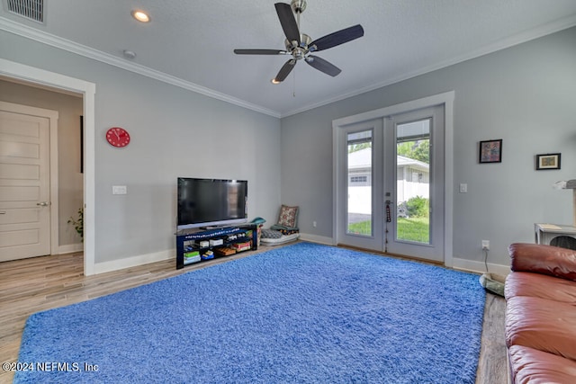 living room featuring wood-type flooring, crown molding, ceiling fan, and french doors