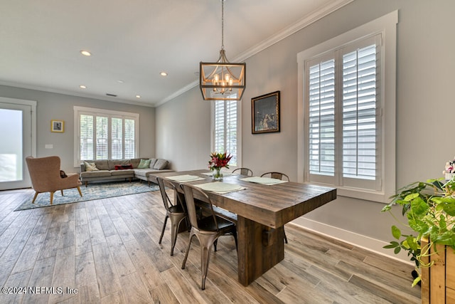 dining room with ornamental molding, an inviting chandelier, and light hardwood / wood-style flooring