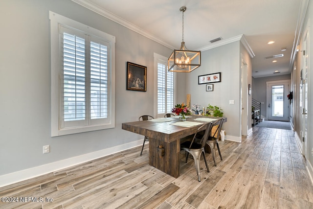 dining room featuring light wood-type flooring, ornamental molding, a notable chandelier, and plenty of natural light