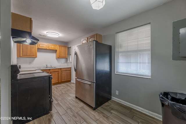 kitchen with sink, light hardwood / wood-style flooring, extractor fan, range with electric stovetop, and stainless steel fridge