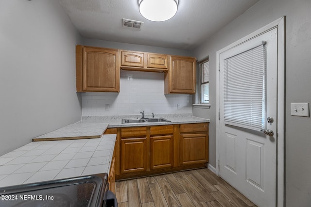 1340 W 11th St, Jacksonville, FL 32209 - kitchen featuring visible vents, wood finished floors, tile countertops, a sink, and backsplash