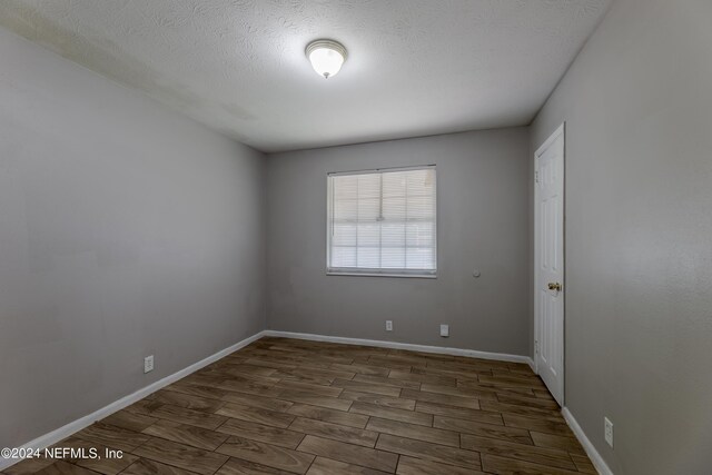 unfurnished room featuring a textured ceiling and dark wood-type flooring