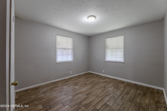 spare room featuring hardwood / wood-style flooring and a textured ceiling