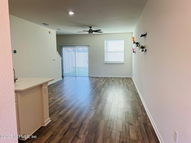 unfurnished living room with a textured ceiling, dark hardwood / wood-style flooring, and ceiling fan