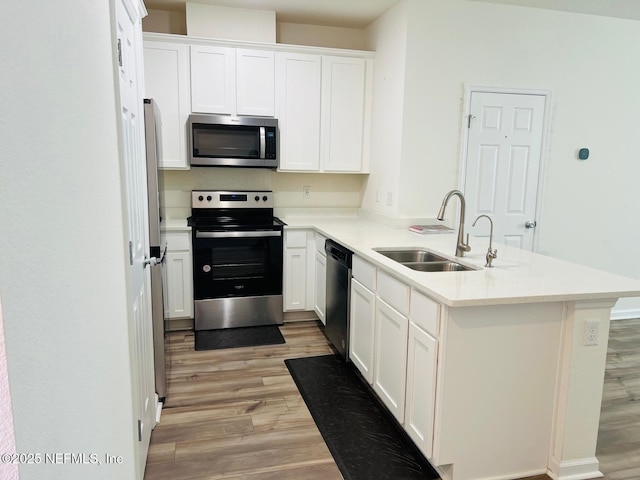 kitchen featuring white cabinets, appliances with stainless steel finishes, light hardwood / wood-style floors, and sink