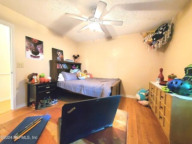 bedroom with a textured ceiling, hardwood / wood-style floors, and ceiling fan