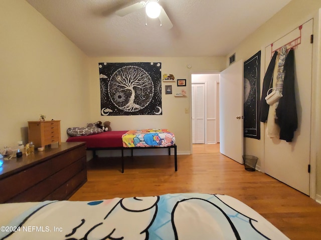 bedroom with ceiling fan, a textured ceiling, and light hardwood / wood-style flooring