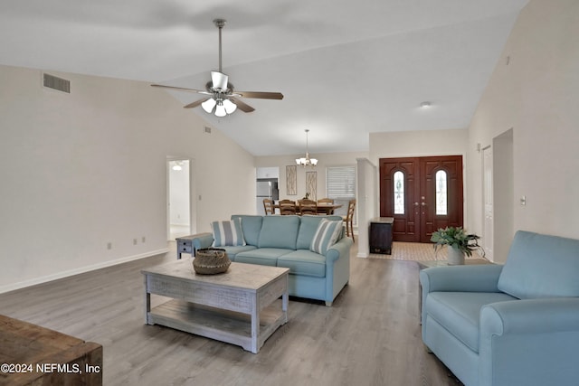 living room with hardwood / wood-style flooring, ceiling fan with notable chandelier, and high vaulted ceiling