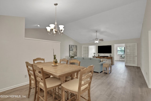 dining room featuring ceiling fan with notable chandelier, light wood-type flooring, and lofted ceiling