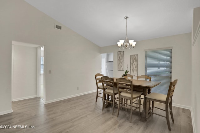 dining room featuring vaulted ceiling, a notable chandelier, and hardwood / wood-style floors