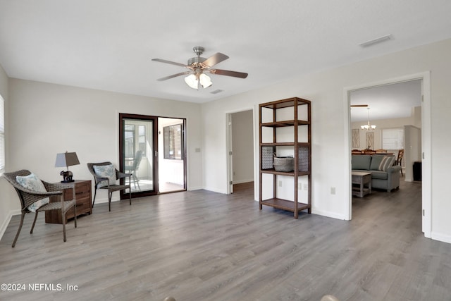 sitting room with ceiling fan with notable chandelier and hardwood / wood-style flooring