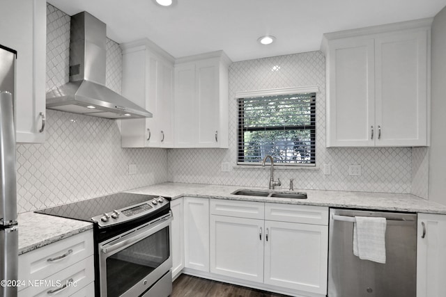 kitchen featuring wall chimney exhaust hood, white cabinetry, appliances with stainless steel finishes, and sink