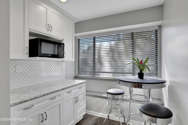 kitchen featuring light stone counters, white cabinets, backsplash, and dark hardwood / wood-style flooring