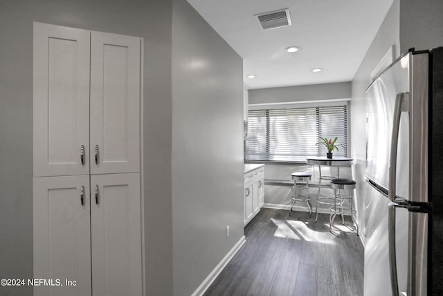 kitchen with stainless steel refrigerator, white cabinetry, and dark hardwood / wood-style floors