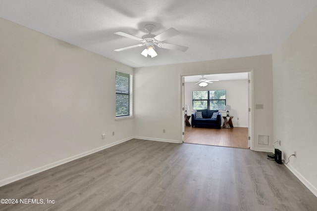 empty room with a textured ceiling, light hardwood / wood-style floors, and ceiling fan