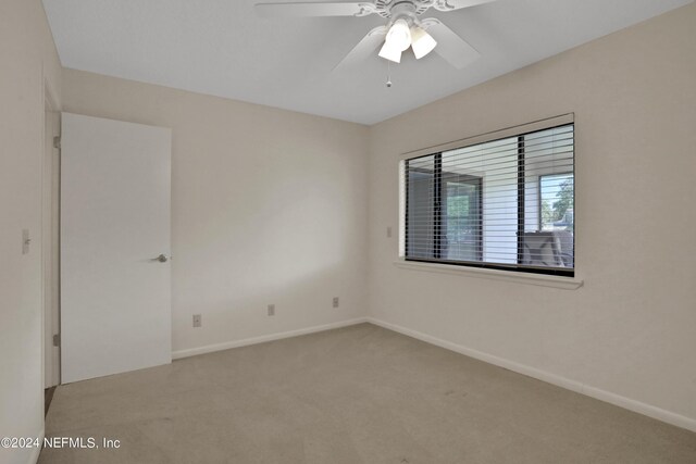 carpeted spare room featuring ceiling fan