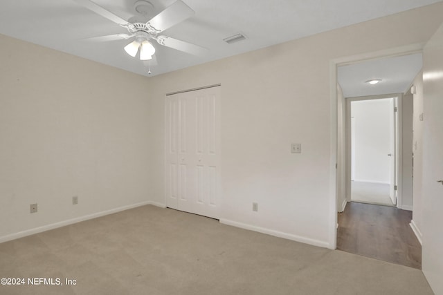 unfurnished bedroom featuring ceiling fan, a closet, and light carpet