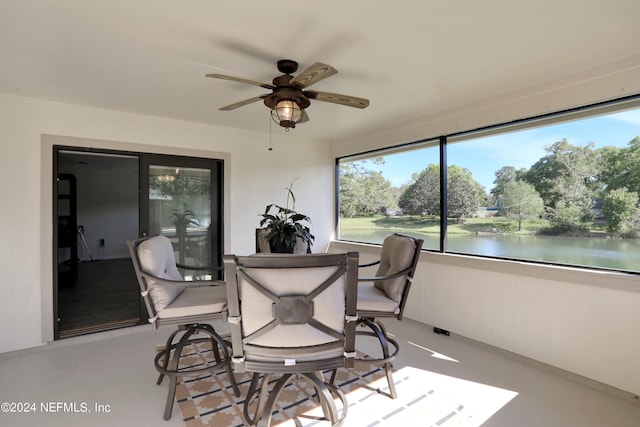 sunroom featuring a water view and ceiling fan