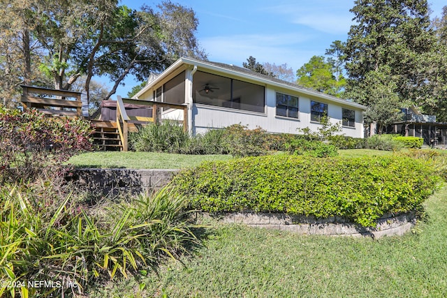 view of front of property with a sunroom, a front yard, and a deck