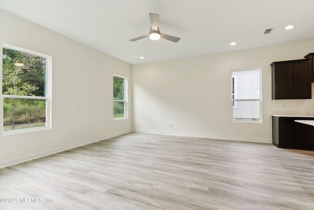 unfurnished living room with light wood-type flooring, ceiling fan, and plenty of natural light