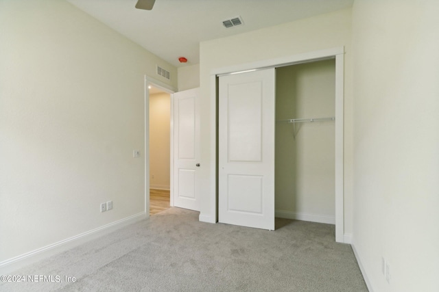 unfurnished bedroom featuring light carpet, a closet, and ceiling fan