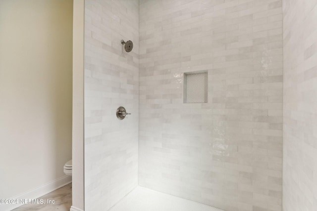 bathroom featuring a tile shower and toilet