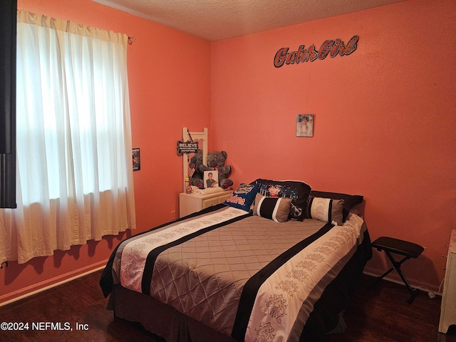 bedroom with a textured ceiling and dark wood-type flooring