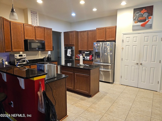 kitchen featuring a breakfast bar, hanging light fixtures, a kitchen island, stainless steel appliances, and light tile patterned floors