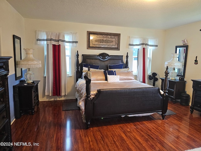 bedroom with multiple windows, a textured ceiling, and dark wood-type flooring