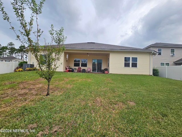 back of property with a yard and central AC