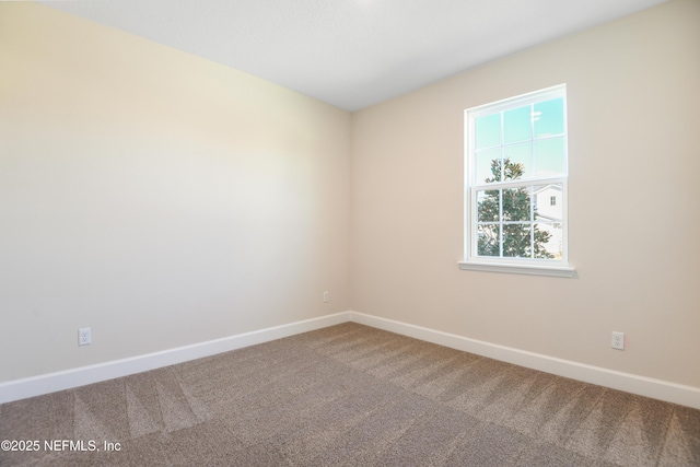 carpeted empty room featuring baseboards